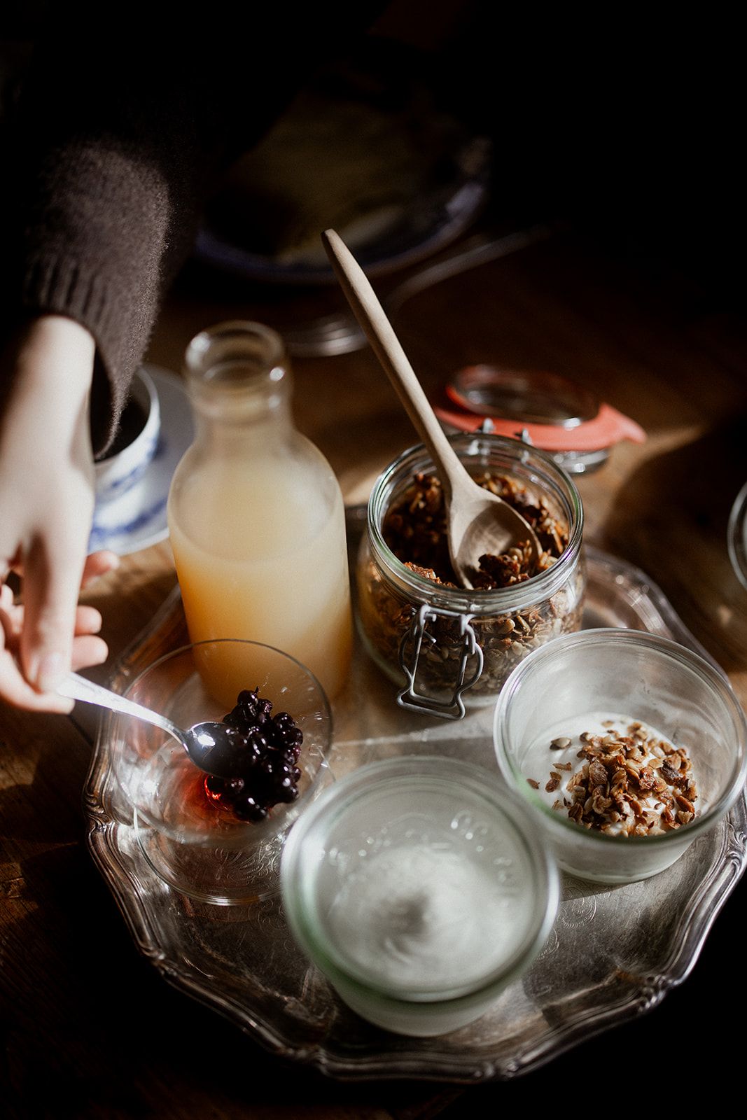 Et frokostbrett med yoghurt, granola, bær og juice i varmt morgenlys.