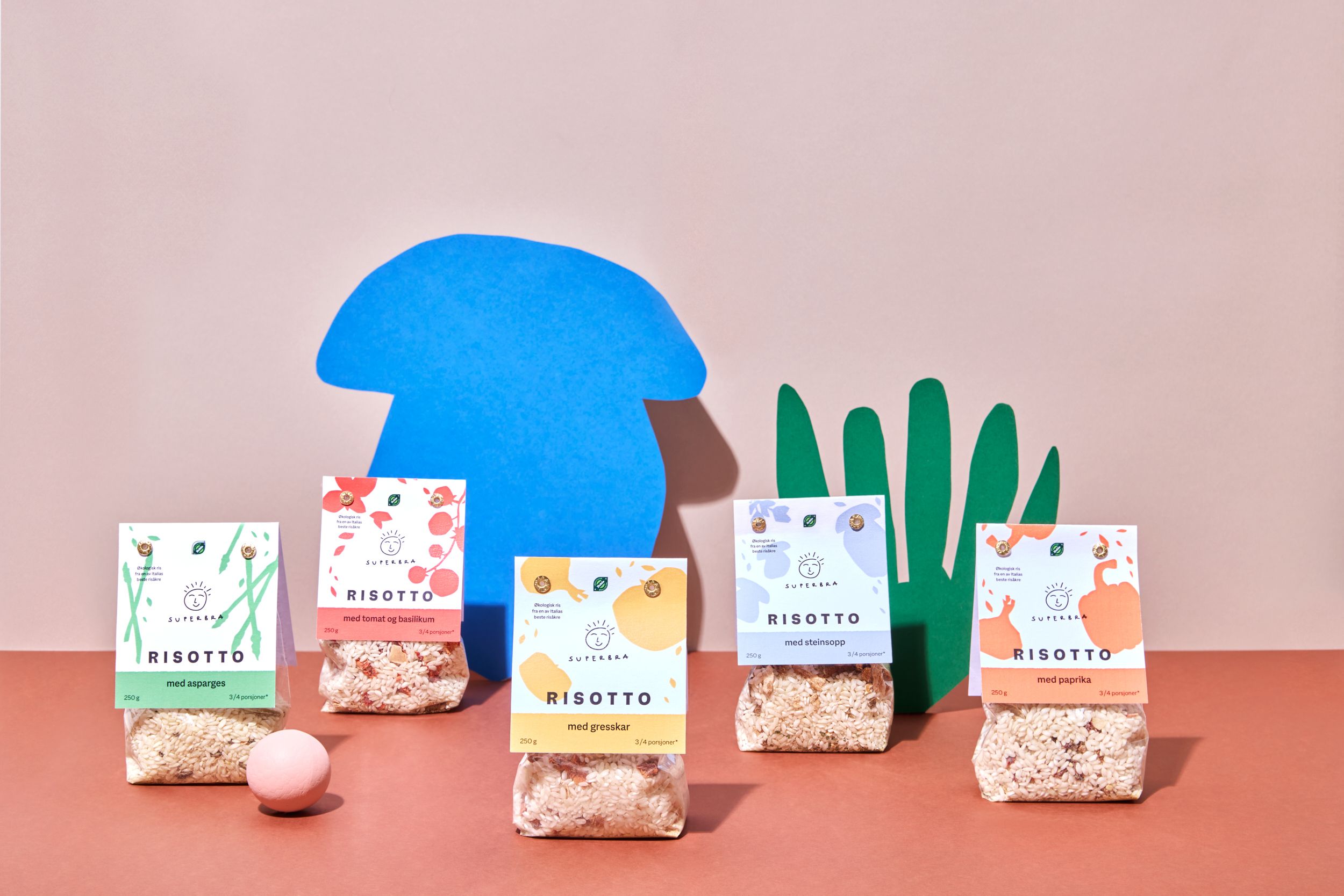 Et utvalg risottoer fra Super Bra, på en oransj-rød bakgrunn, forran en fargerrike utklipp av sopp og kaktus.