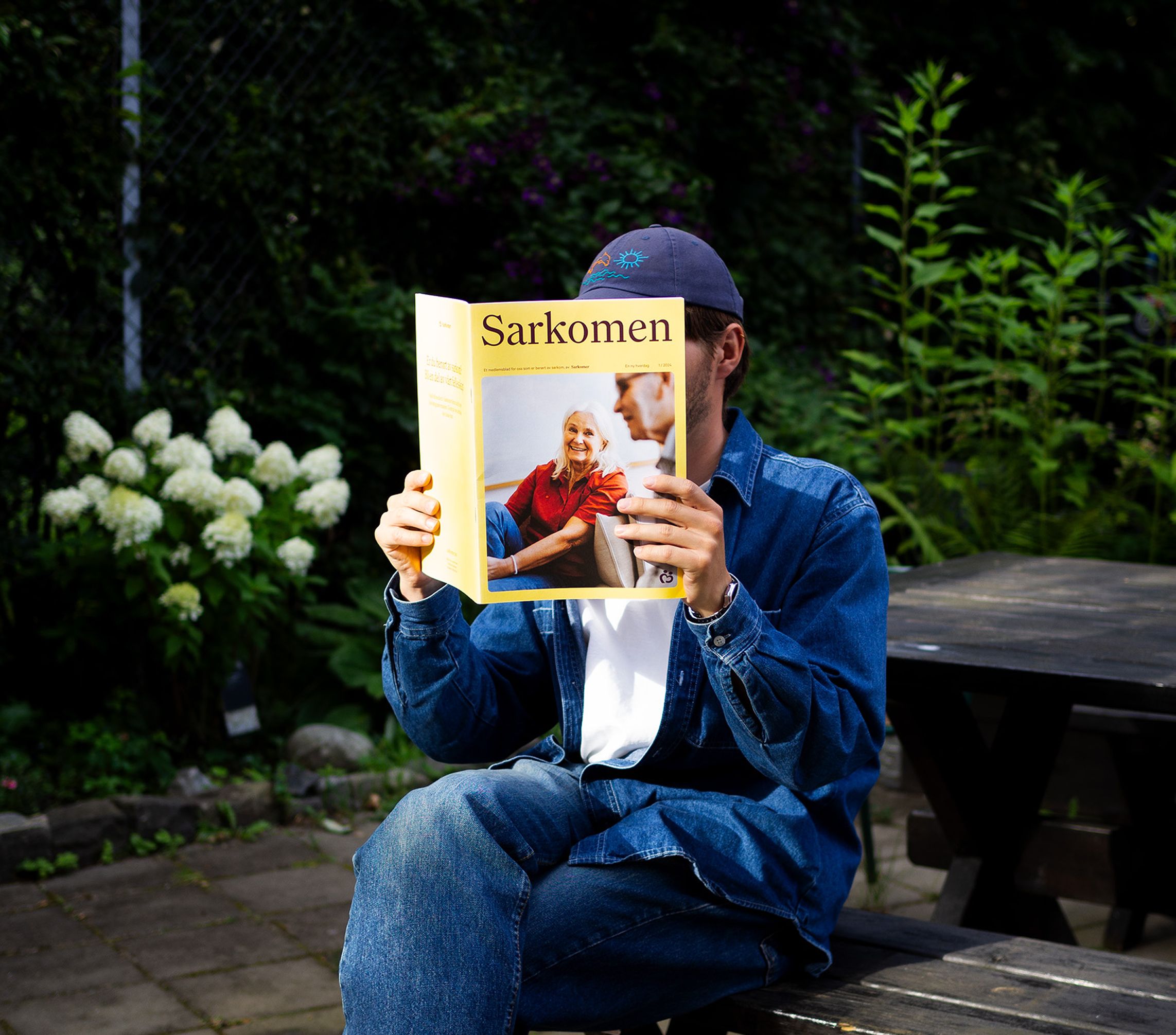 En person som sitter å leser medlemsbaldet Sarkomen